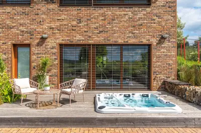 a patio with a hot tub in front of a brick building at Rezidence Malá Louka in Kublov