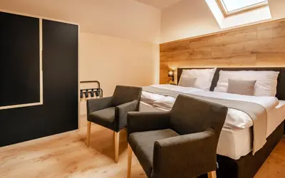 a bedroom with a large bed and two chairs at Penzion U Mě in Obora