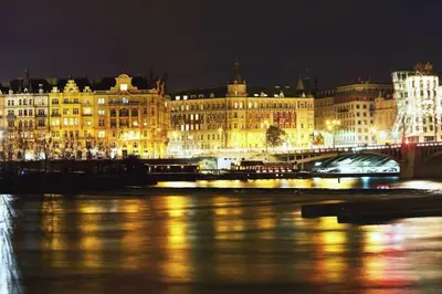 a large building with lights on the water at night at Green Park View apartment in Prague