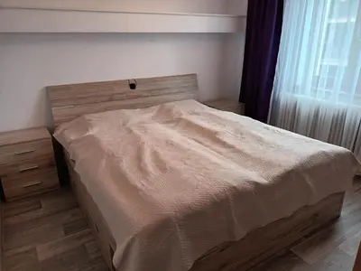 a bedroom with a bed with a wooden headboard and a window at Byt v řadovém domě in Sadská