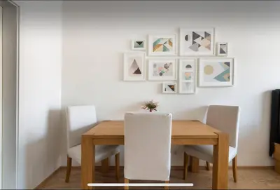 a dining room table with white chairs and pictures on the wall at Rezidence Garden Towers - studio s parkováním in Prague