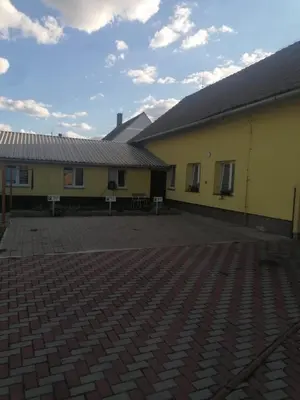 a yellow building with a brick courtyard in front of it at Ubytování Louny in Louny
