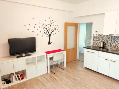 a kitchen with a table with a tv and a tree on the wall at Apartment Žižkov in Prague