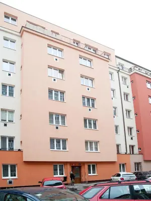 a large pink building with cars parked in a parking lot at Apartment Žižkov in Prague