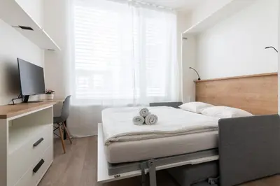a bedroom with a bed with a desk and a television at Studio Mozart, Free Onsite Parking, Air Conditioning, 1Gbs WiFi in Prague