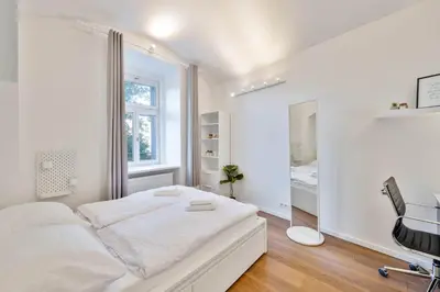 a white bedroom with a bed and a desk at Elegant Apartments close to Center & Bike Path in Prague