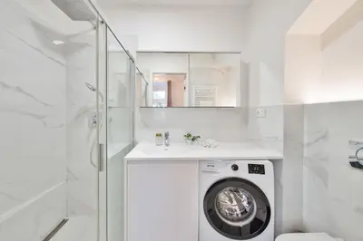 a white bathroom with a washing machine and a shower at Elegant Apartments close to Center & Bike Path in Prague