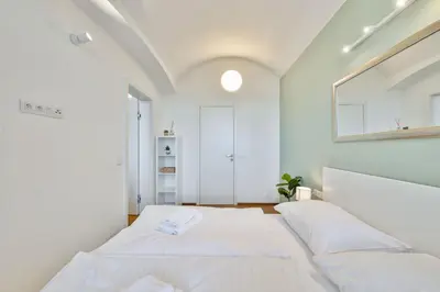 a white bedroom with a bed and a mirror at Elegant Apartments close to Center & Bike Path in Prague
