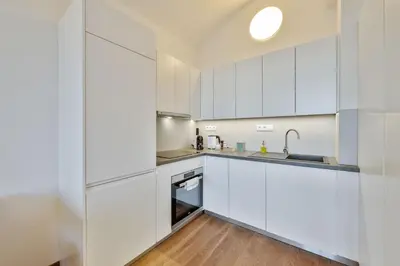 a kitchen with white cabinets and a sink at Elegant Apartments close to Center & Bike Path in Prague