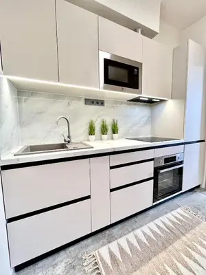 a white kitchen with a sink and a microwave at GeraStay Sokolska in Prague