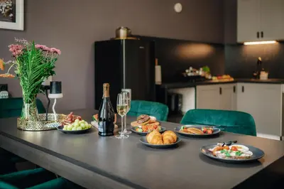 a table with plates of food and a bottle of wine at Cinema Apartment Billiard & Foosball - City Centre in Prague