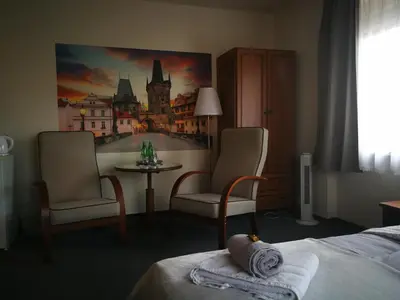 a hotel room with a bed and two chairs and a table at Pension Villa Marit in Prague