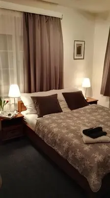 a bedroom with a large bed with two lamps and a window at Pension Villa Marit in Prague