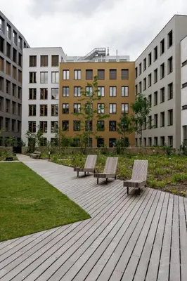 two benches sitting on a boardwalk in a park with buildings at Prague Days - One-bedroom Apartment with Garage Parking and Balcony in Prague