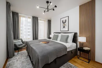 a bedroom with a large bed and a chair at Prague Days - One-bedroom Apartment with Garage Parking and Balcony in Prague
