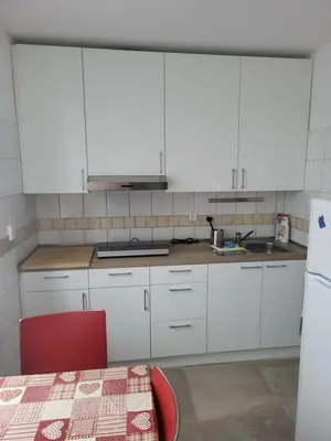 a kitchen with white cabinets and a table and a sink at Komárov Apartment 2 in Komárov