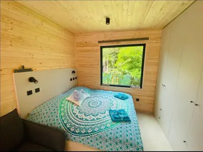 a small bedroom with a bed in a wooden cabin at Glamping paradise with wellness in Dolní Břežany