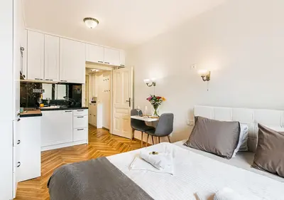 a white bedroom with a bed and a kitchen at Apartment Linda Prague in Prague