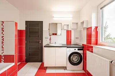 a red and white kitchen with a washing machine at U tří koček in Herink