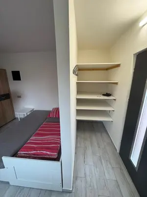 a small room with a bed and shelves at U tří koček in Herink