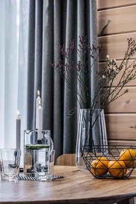 a wooden table with a vase of oranges and a candle at Finskä chata in Samopše