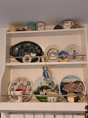a shelf filled with plates and bowls and dishes at Лесной Коттедж Нова in Živohošť