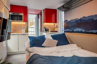 a kitchen with red cabinets and a couch with blue pillows at Houseboat Prague with Paddle Boat -Sail, Explore and Relax in Prague