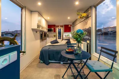 a small room with a bed and a table with flowers at Houseboat Prague with Paddle Boat -Sail, Explore and Relax in Prague