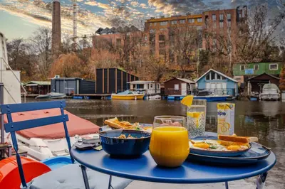 a table with a plate of food and a glass of orange juice at Houseboat Prague with Paddle Boat -Sail, Explore and Relax in Prague