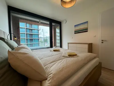 a large bed in a room with a large window at Smíchov City apartment - Albrigtova in Prague