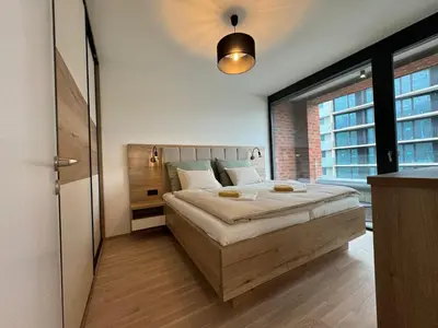 a bedroom with a bed and a large window at Smíchov City apartment - Albrigtova in Prague