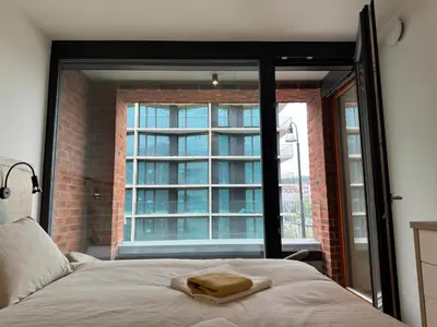 a bedroom with a bed and a large window at Smíchov City apartment - Albrigtova in Prague