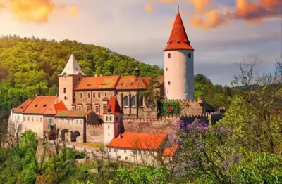 a castle with a tower on a hill with trees at Apartmán Roztoky u Křivoklátu in Roztoky