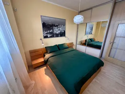 a bedroom with a green bed and a mirror at Apartment Českomoravská - O2 Arena Prague in Prague