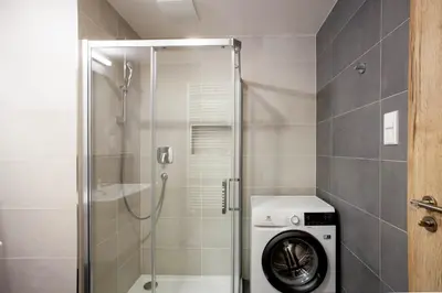 a bathroom with a shower and a washing machine at Blueground Holešovice family-friendly nr park PRG-3 in Prague