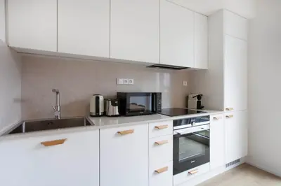 a kitchen with white cabinets and a sink and a microwave at Blueground Holešovice family-friendly nr park PRG-3 in Prague