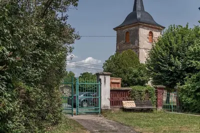 a gate in front of a building with a tower at Fara Bošín in Křinec