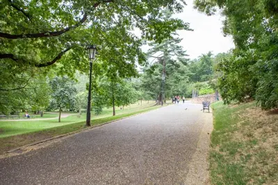 a path in a park with a bench and trees at Blueground - Vrsovice, furnished in Prague