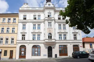 a white building on a street with cars parked in front at Blueground - Vrsovice, furnished in Prague