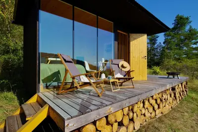 a house with glass windows and chairs on a wooden deck at Ztracený Sad - Glamping na samotě in Nečín
