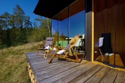 two chairs and a table on a deck of a house at Ztracený Sad - Glamping na samotě in Nečín