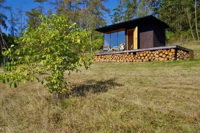 a house built around a pile of fire logs at Ztracený Sad - Glamping na samotě in Nečín