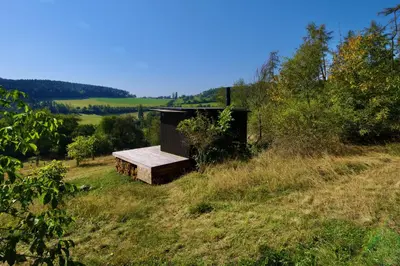 a building in the middle of a grassy field at Ztracený Sad - Glamping na samotě in Nečín