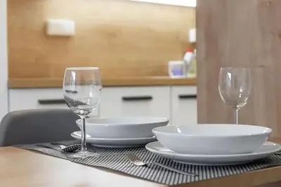 a table with two wine glasses and a plate on it at Central Tiny Flat, 1GB WiFi, SMART TV, Air Condition in Prague