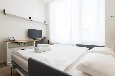 a white bedroom with a bed and a tv at Central Tiny Flat, 1GB WiFi, SMART TV, Air Condition in Prague