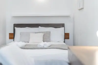 a white bed with two towels on top of it at Rentero Apartment, 10 minutes Wenceslas Square, Prague in Prague