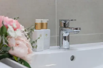 a bathroom sink with a bottle of soap and flowers at SMART Studio with Ultra Fast 1Gbps WiFi and Air Conditioning in Prague