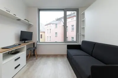 a living room with a couch and a desk with a computer at SMART Studio with Ultra Fast 1Gbps WiFi and Air Conditioning in Prague