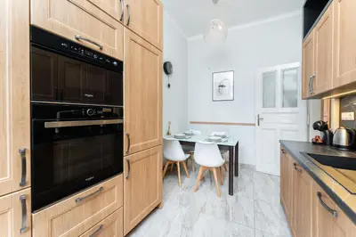 a kitchen with wooden cabinets and a table with white chairs at Rentero Friendly Apartment near Wenceslas Square in Prague