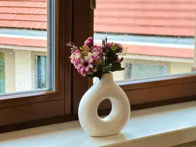 a white vase with flowers sitting on a window sill at STUDIO KRÁLOVICE Apartment in Prague